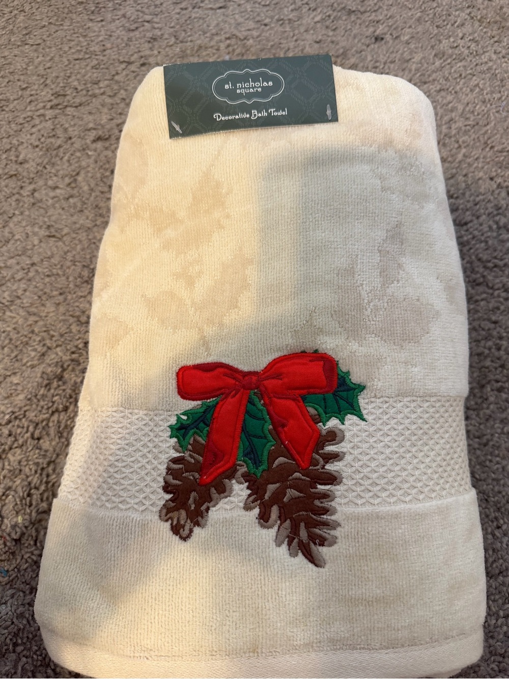St. Nicholas Square cream holiday towel with red bow and pinecone appliqué
